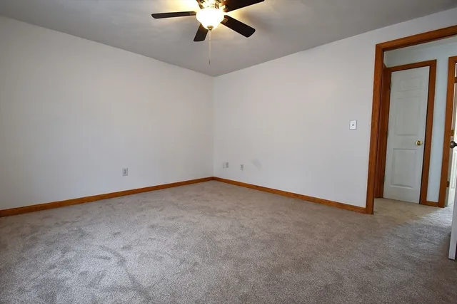 an empty room with a chandelier fan and windows