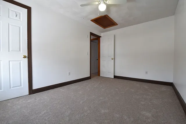 an empty room with a chandelier fan and wooden floor