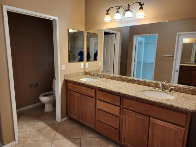 a bathroom with a granite countertop sink toilet a large mirror and a mirror