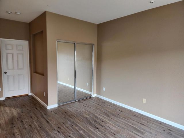 a view of an empty room with wooden floor and closet