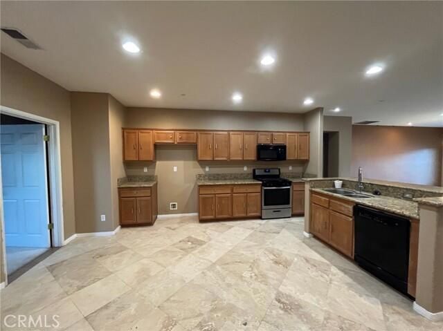 a kitchen with stainless steel appliances granite countertop a stove top oven a sink and a refrigerator