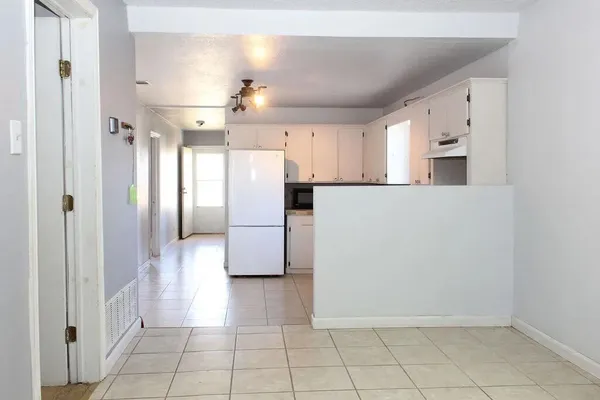 a view of a refrigerator in kitchen and white cabinets