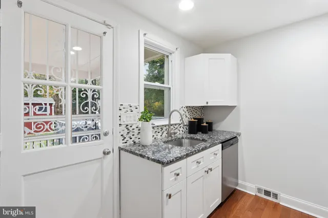 a kitchen with stainless steel appliances granite countertop a sink and a white cabinets