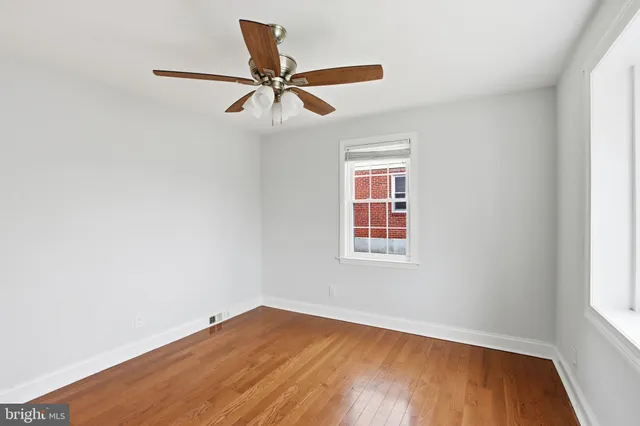 an empty room with wooden floor fan and windows