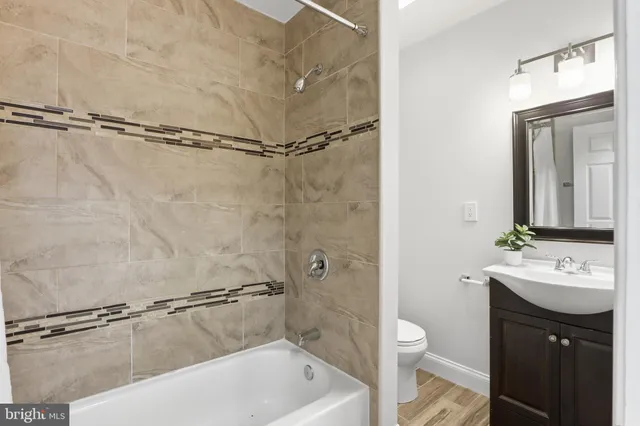 a bathroom with a granite countertop sink a toilet and shower
