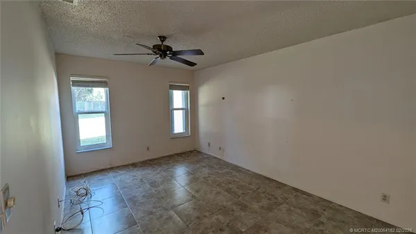 an empty room with windows and fan