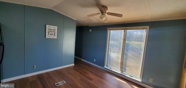 an empty room with wooden floor chandelier and windows
