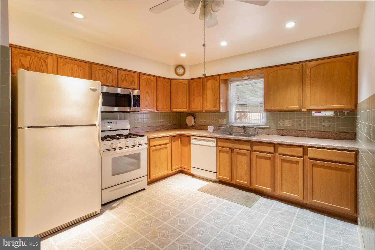 418 Densmore Road Philadelphia, PA 19116 - Photo 11 of 25 a kitchen with granite countertop a refrigerator a sink and white cabinets