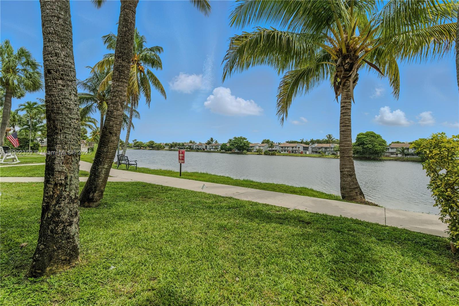 6825 Northwest 169th Street, Unit 54H Hialeah, FL 33015 - Photo 30 of 46 a view of a lake with a big yard and palm trees
