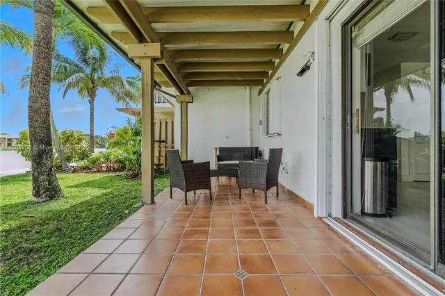 a patio with table and chairs and potted plants