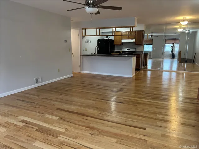 a view of a room with kitchen island stainless steel appliances wooden floor and living room view