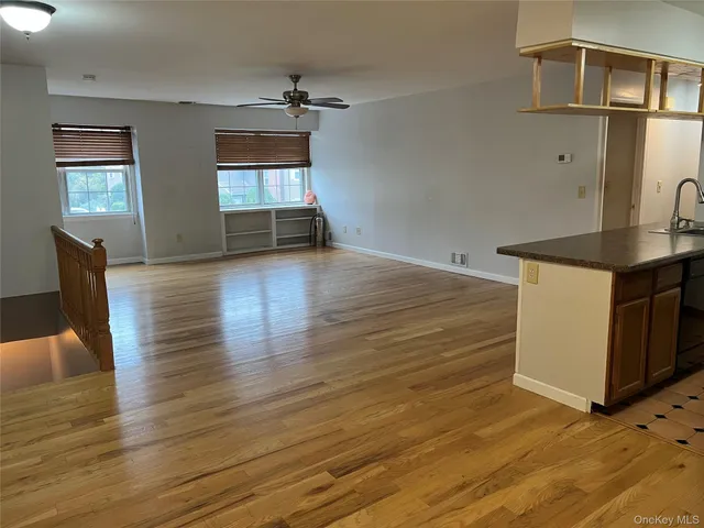 a view of kitchen and empty room with wooden floor