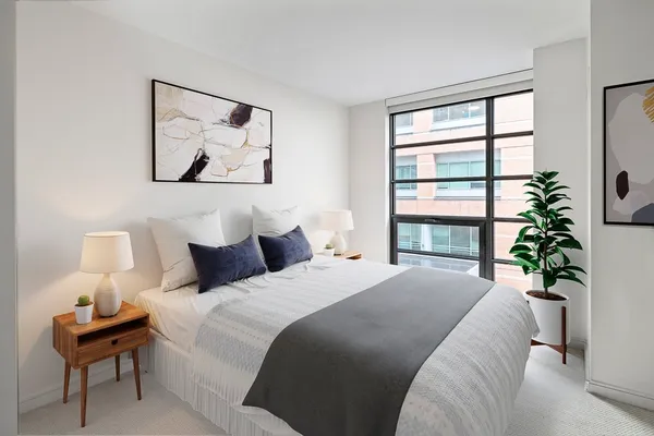 a bedroom with bed and a potted plant next to a window