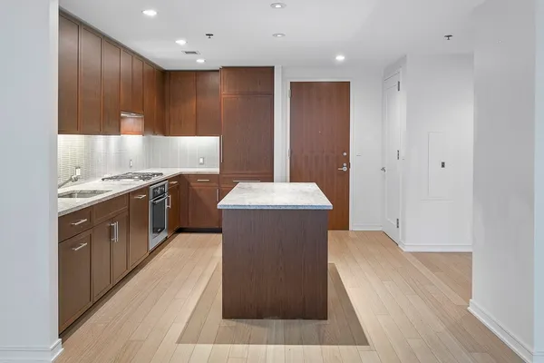 a large kitchen with a large counter top a sink stainless steel appliances and cabinets