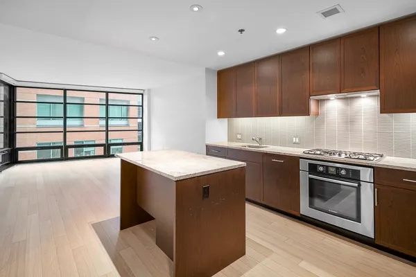 a kitchen with kitchen island granite countertop wooden cabinets and a stove