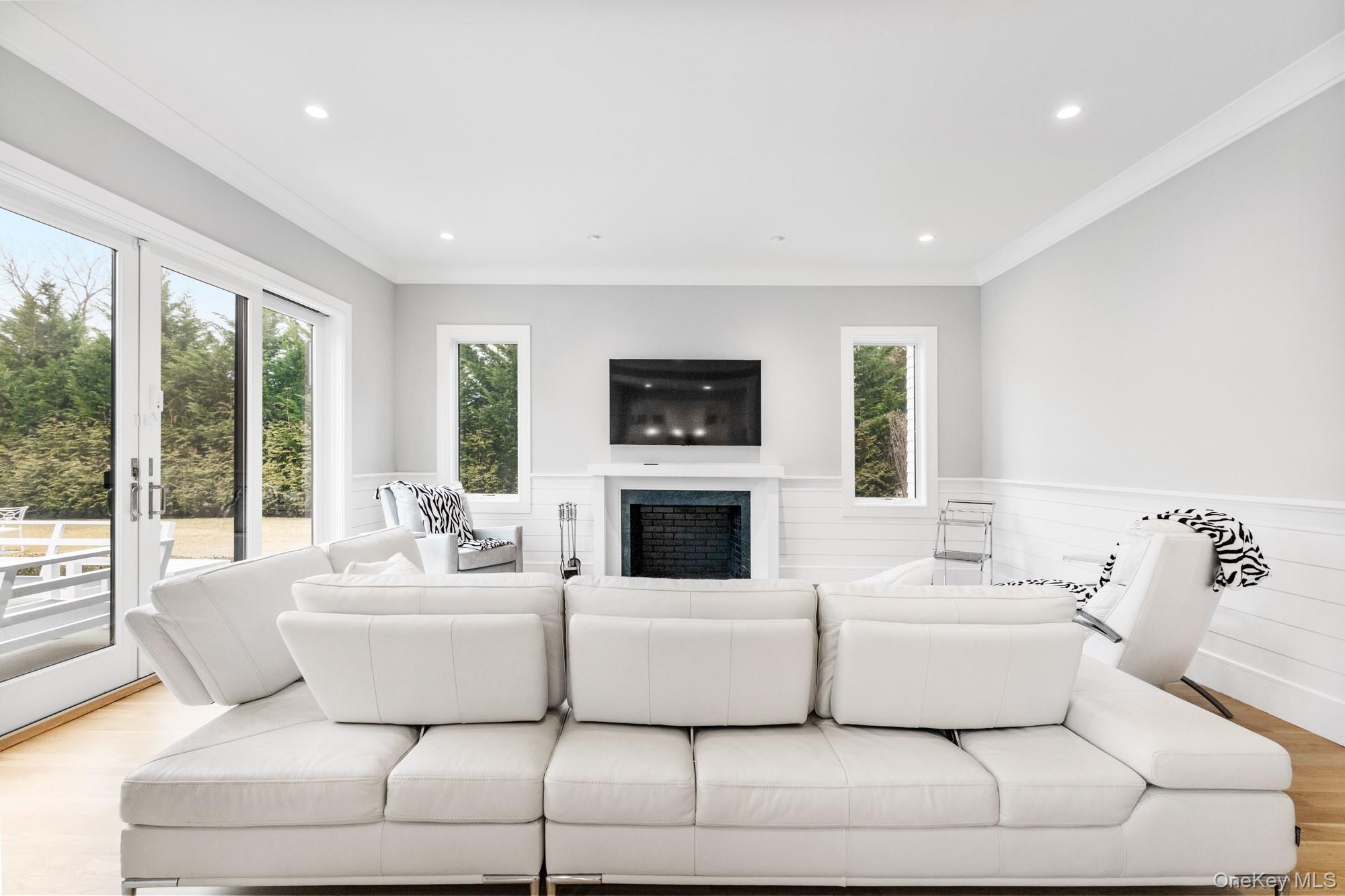 240 Head Of Pond Road Water Mill, NY 11976 - Photo 20 of 40 Living room featuring a wainscoted wall, wood finished floors, a fireplace, recessed lighting, and crown molding