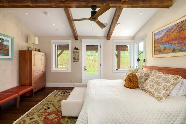 a bedroom with a bed painting on wall and a large window