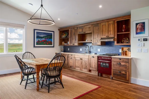 a kitchen with stainless steel appliances granite countertop a stove a sink a microwave a dining table and chairs with wooden floor