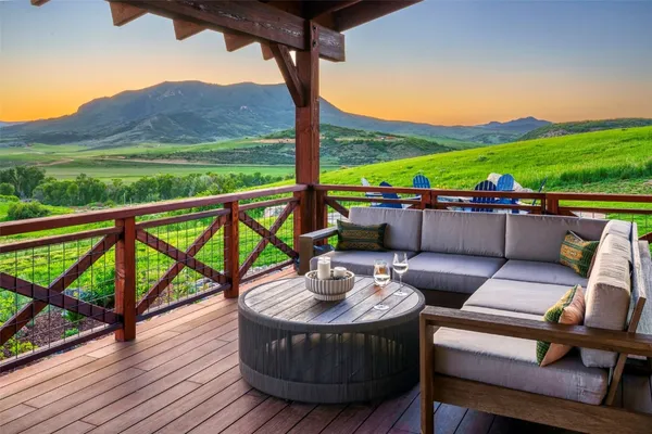 a view of a patio with couches chairs under an umbrella with wooden floor