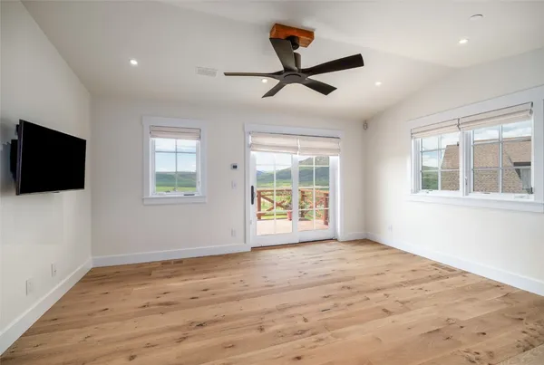 a view of an empty room with a window and wooden floor