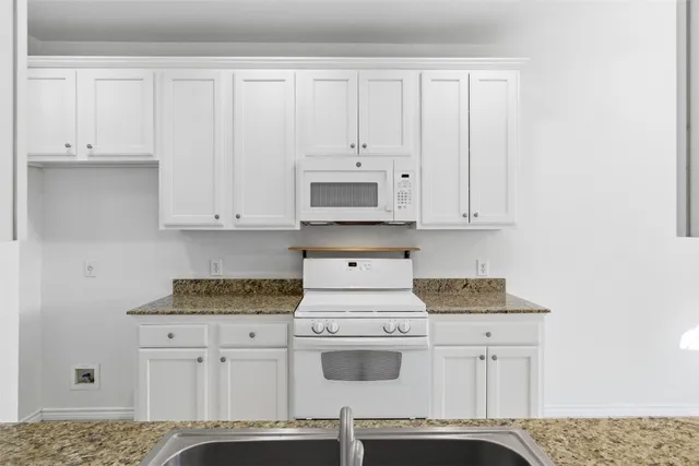 a kitchen with stainless steel appliances granite countertop white cabinets and a stove