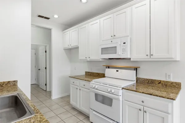 a kitchen with granite countertop white cabinets and white appliances