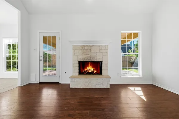 an empty room with wooden floor fireplace and windows