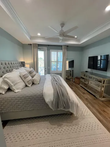 a bedroom with a bed a mirror on dresser and a flat screen tv
