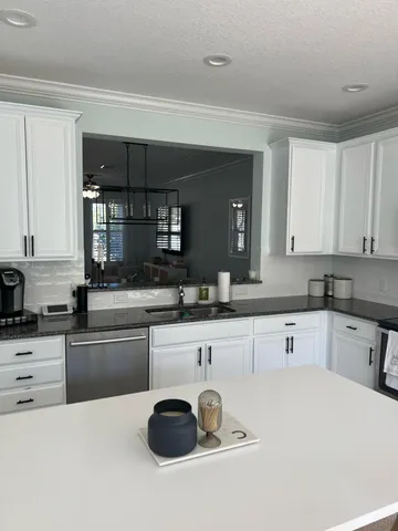 a kitchen with granite countertop a sink and white cabinets