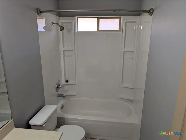 a view of an empty room with wooden floor and fan