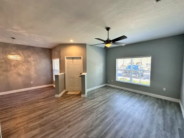 a view of an empty room with a window and wooden floor