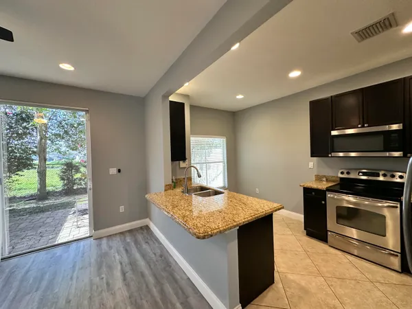 a kitchen with kitchen island granite countertop stainless steel appliances cabinets a sink and a counter top space