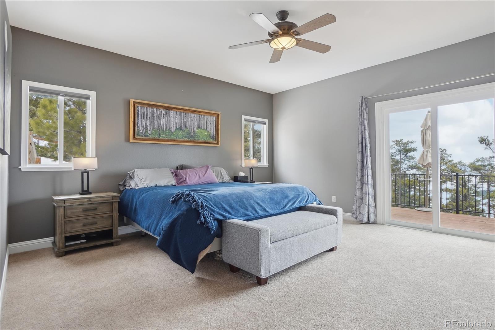 13084 Deer Ridge Way Larkspur, CO 80118 - Photo 18 of 48 a spacious bedroom with a large bed and a chandelier