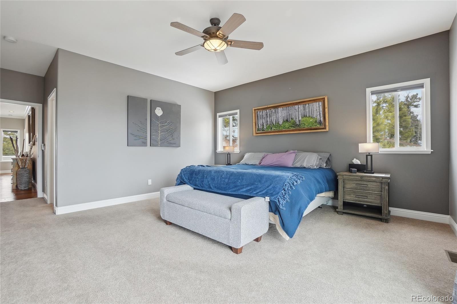 13084 Deer Ridge Way Larkspur, CO 80118 - Photo 19 of 48 a spacious bedroom with a bed and a chandelier