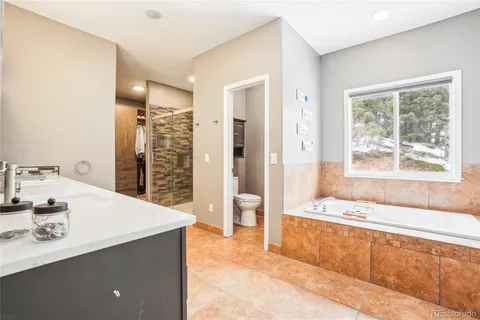 a spacious bathroom with a tub a sink and a large mirror