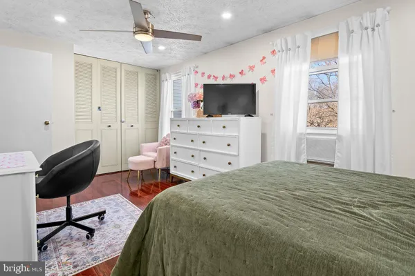 a bedroom with a bed a flat screen tv and dresser