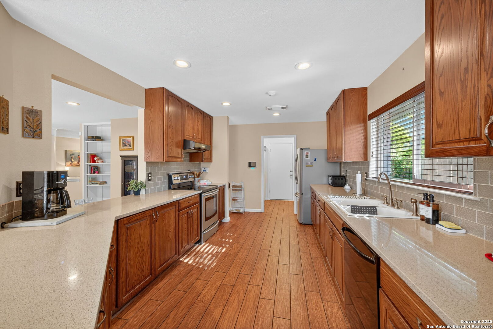 1902 Indian Meadows Drive San Antonio, TX 78230 - Photo 11 of 31 a large kitchen with stainless steel appliances a large counter top a sink dishwasher and a stove top oven with wooden floor