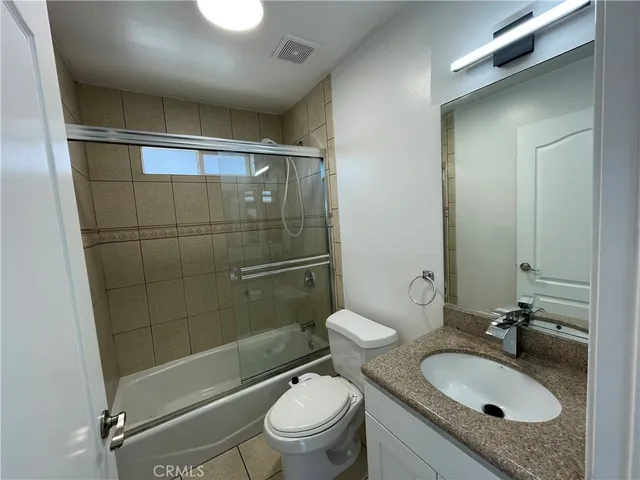 a bathroom with a granite countertop sink toilet mirror and shower