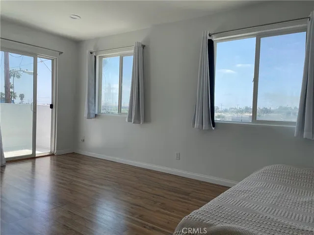 a view of a bedroom with wooden floor and a window