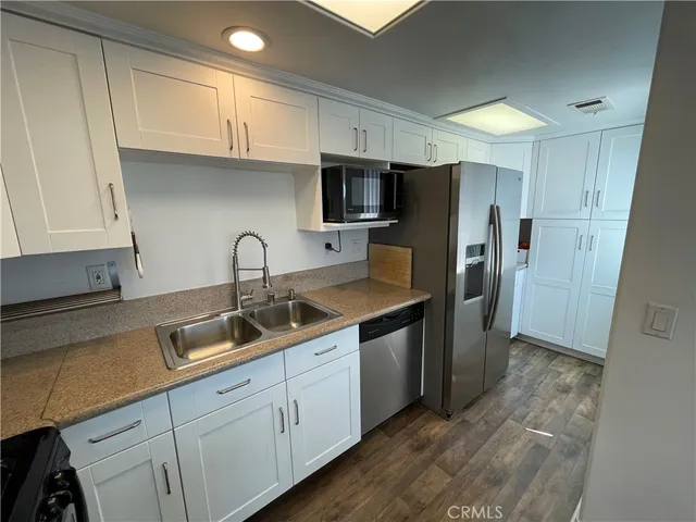 a kitchen with stainless steel appliances granite countertop a sink refrigerator and cabinets