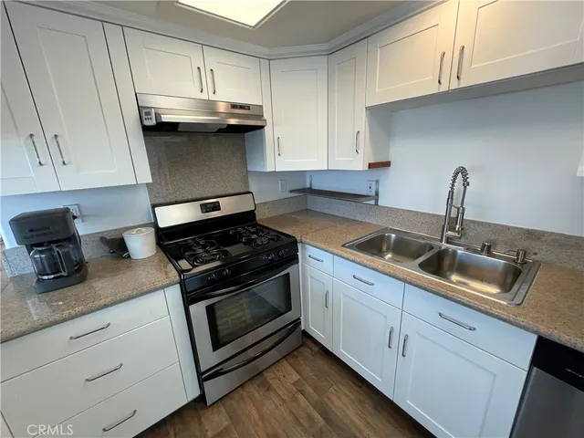 a kitchen with granite countertop white cabinets and a stove