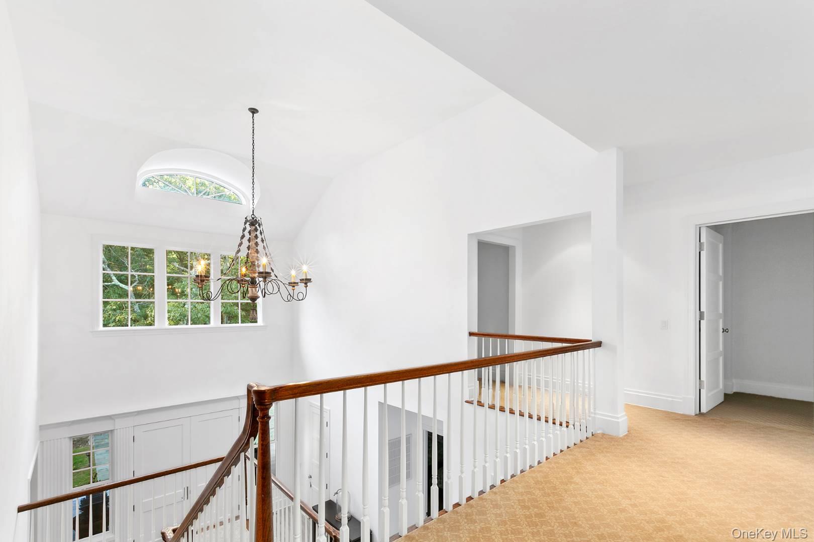 1477 Deerfield Road Water Mill, NY 11976 - Photo 17 of 17 Hall featuring an upstairs landing, plenty of natural light, lofted ceiling, a chandelier, and light carpet