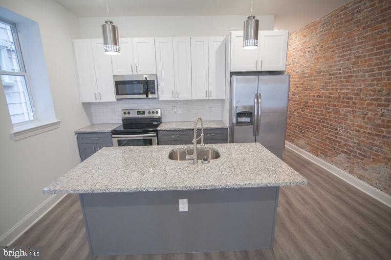 1829 North 33rd Street, Unit 1 Philadelphia, PA 19121 - Photo 1 of 9 a kitchen with stainless steel appliances granite countertop a sink stove and refrigerator