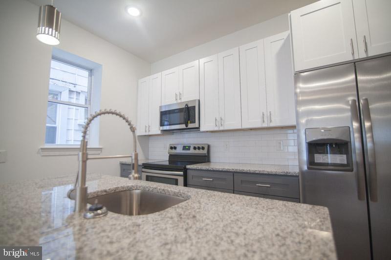 1829 North 33rd Street, Unit 1 Philadelphia, PA 19121 - Photo 9 of 9 a kitchen with stainless steel appliances granite countertop a sink a stove and a refrigerator