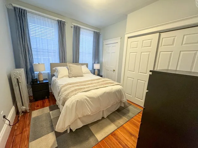 a bedroom with a bed wooden floor and chair