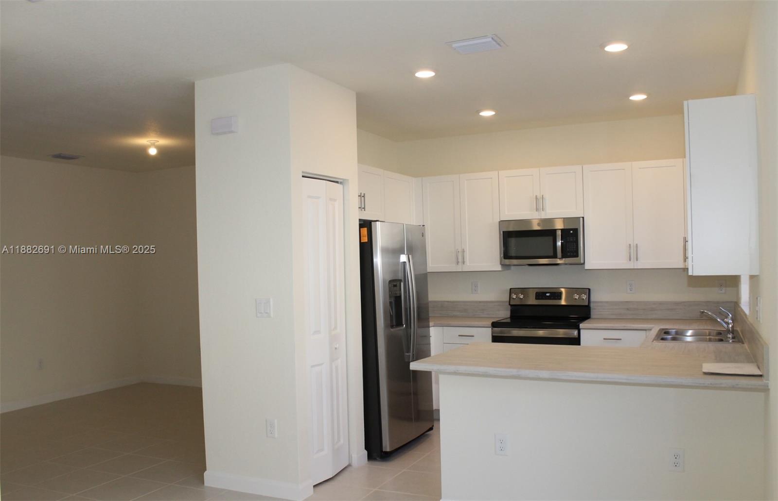 11100 West 33rd Way, Unit 11100 Hialeah, FL 33018 - Photo 7 of 26 a kitchen with stainless steel appliances a refrigerator a stove a microwave and cabinets