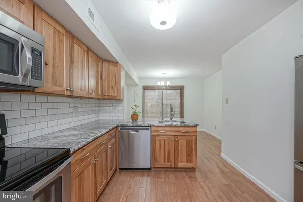 a kitchen with stainless steel appliances granite countertop wooden cabinets a sink and dishwasher a stove top oven with wooden floor