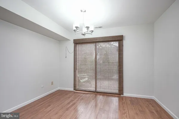 an empty room with wooden floor chandelier fan and windows