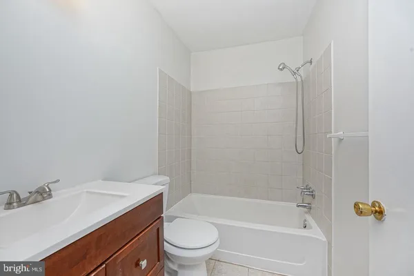 a bathroom with a granite countertop bathtub shower sink vanity and toilet