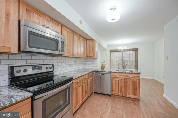a kitchen with appliances cabinets and a wooden floor